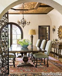 a dining room table with chairs and chandelier in the middle of an archway