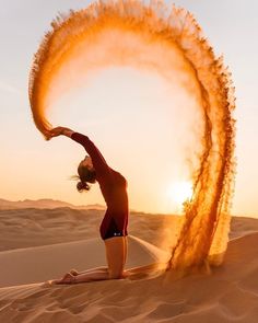 a woman doing yoga in the desert with her arms stretched out and fire spinning around her