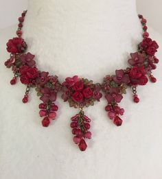 Roses are Red Necklace is so romantic. With several clusters of flowers and a poise of red roses in the center of each. This necklace is a gorgeous stunning red with a hints of green flowers that compliments the red. This piece is set off nicely with pretty red drops hanging off of each cluster. Every one needs a stunning statement red necklace in their collection. Colleen has been creating her unique style of vintage jewelry for more than 30 years. All of our pieces come with an engraved tag wi Red Flower-shaped Necklace With Rose Design, Red Flower Necklace With Rose Design, Red Floral Rose Design Necklace, Red Rose Design Flower Necklace, Red Rose Jewelry For Wedding, Red Rose Design Necklace For Wedding, Pretty Valentines, Roses Are Red, Red Necklace