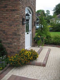 a brick house with flowers growing in the front yard