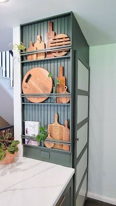 a kitchen with green cabinets and white counter tops in front of a spiral staircase case