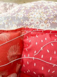 someone is stitching together some red and white pillows