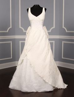 a white wedding dress on display in a room with blue walls and wood flooring