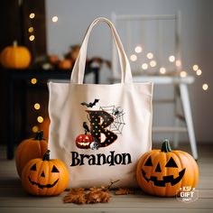 two pumpkins and a tote bag with the name brandon on it sitting next to halloween decorations