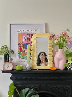 there is a mirror and vase on top of the fireplace mantel with flowers in it