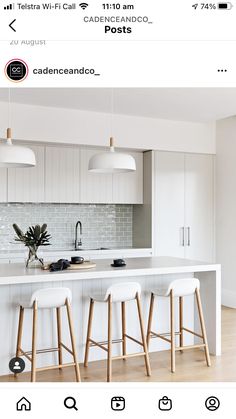 a kitchen with three stools next to an island in the middle of the room