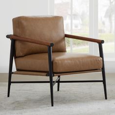 a brown leather chair sitting on top of a carpeted floor next to a window