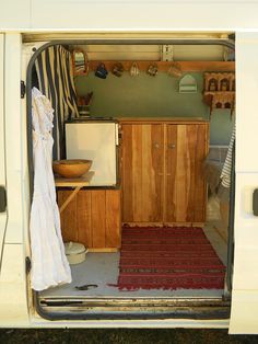 the inside of a van with an open door and clothes hanging out to dry off