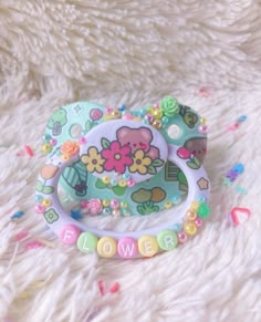 a baby's pacifier with flowers on it sitting on a fluffy white surface