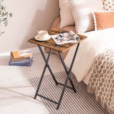 a small table with a magazine on it next to a bed and pillows in a bedroom