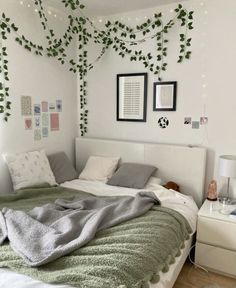 a bedroom with white walls and green plants on the wall above the bed, along with two framed pictures