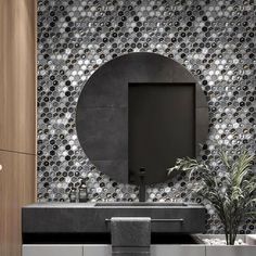 a modern bathroom with black and white mosaic tiles on the wall, round mirror above the sink