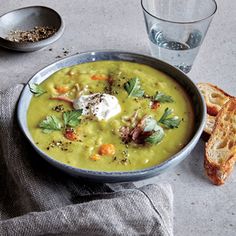 a bowl filled with soup next to two slices of bread on top of a table