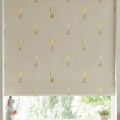 a white window with yellow hot air balloons on the roman blind in front of it