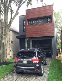 a black jeep parked in front of a house with a large tree and grass area