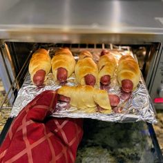 hotdogs wrapped in bacon are being cooked in an oven with foil on top