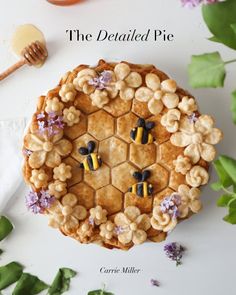 a pie with bee decorations on it sitting next to some flowers and a honey comb