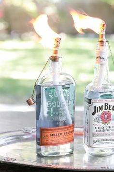 two empty bottles sitting on top of a table with fire coming out of the bottle