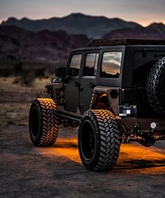 a black jeep parked in the desert at night with bright lights on it's tires