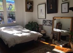 a bed sitting in a bedroom next to a window with pictures hanging on the wall