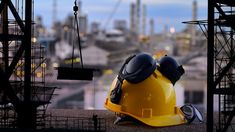 a hard hat and goggles on top of a construction site with the city in the background