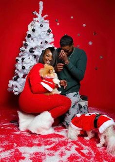 a man and woman pose with their dog in front of a christmas tree