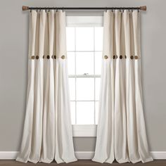 a white curtain with gold buttons hanging on the side of it in front of a window