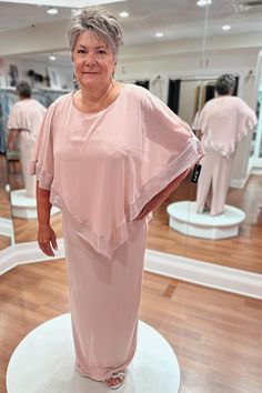 an older woman in a pink dress standing on a white pedestal with other mannequins behind her