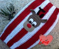 a red and white striped knitted hat with reindeer on the front, one eye closed