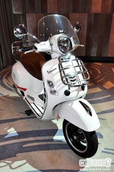 a white motor scooter parked in front of a wall with wood paneling