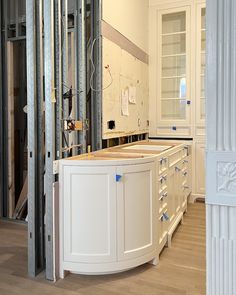 an unfinished kitchen with white cabinets and wood flooring in the background is being built