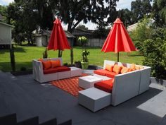 an outdoor seating area with red umbrellas and orange pillows