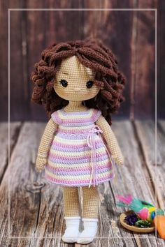 the doll is wearing a pink and white striped dress with her hair in pigtails