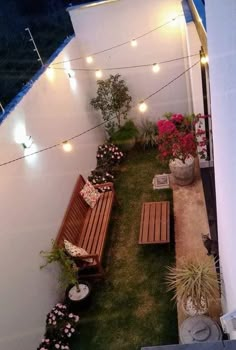 an overhead view of a small backyard with lights strung over the grass and wooden benches