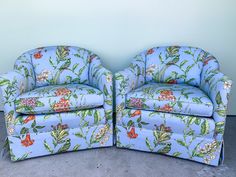 two blue chairs sitting next to each other on top of a carpeted floor in front of a wall