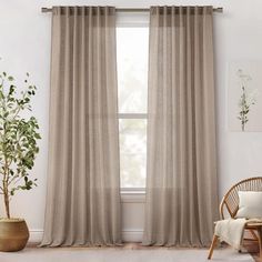 a living room with a chair, window curtain and potted plant in the corner