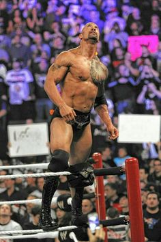 a man standing on top of a wrestling ring in front of a large group of people