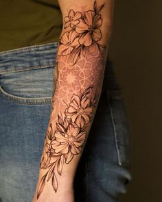 a woman's arm with flowers on it and an intricate design in the middle