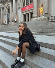 a woman is sitting on some steps in front of a building