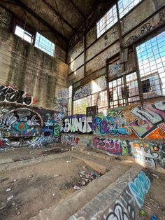 an abandoned building with graffiti all over the walls and floor, along with several windows