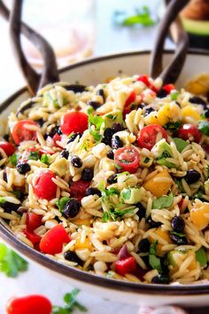 a bowl full of rice salad with olives, tomatoes and other vegetables in it