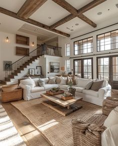 a living room filled with lots of furniture next to a stair case in front of a window