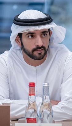 a man sitting at a table with two bottled water bottles in front of his face