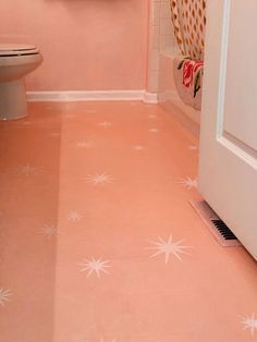 a bathroom with pink walls and white stars painted on the floor next to a toilet