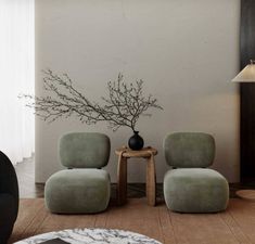 two chairs and a table with a vase on it in a room that has white walls