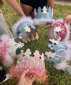 several people are holding crowns in the grass with pink and blue tinsels on them