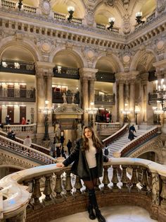 a woman standing on top of a staircase in a building