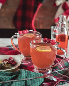 two glasses filled with raspberry tea on top of a plaid table cloth next to silverware