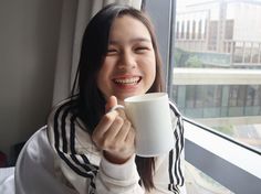 a woman is holding a coffee cup and smiling