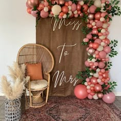 a chair sitting in front of a sign that says miss to mrs with balloons and greenery